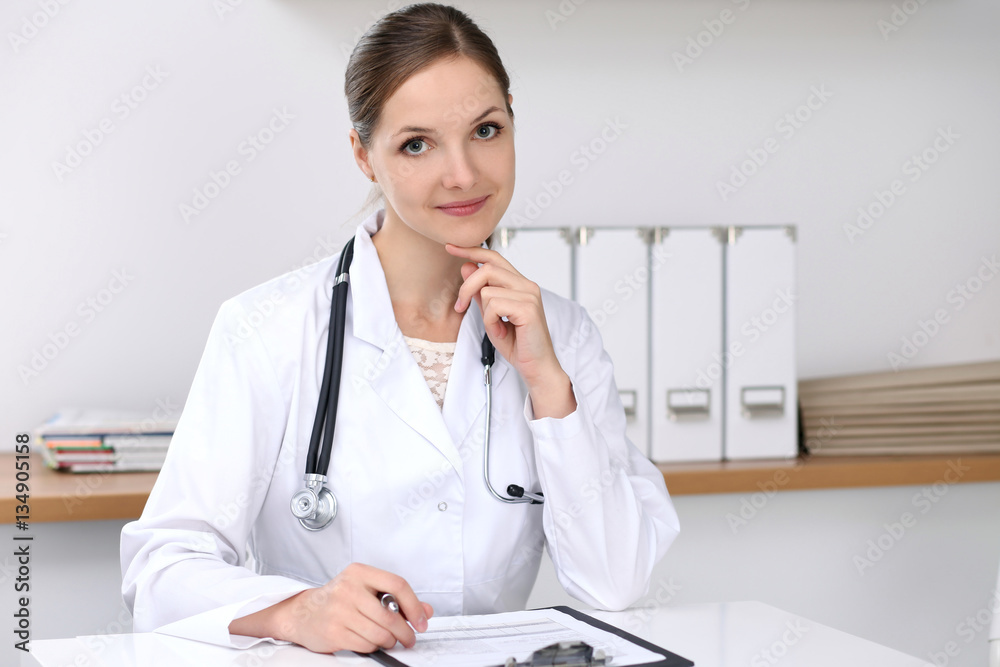 Doctor woman filling up medical form while sitting at the desk. Medicine and health care concept Doctor woman filling up medical form while sitting at the desk. Medicine and health care concept
