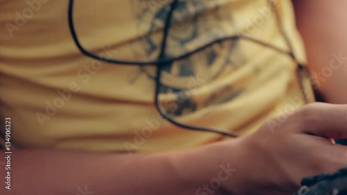 A teenage boy sitting in a park listening to music. Boy with headphones outdoors