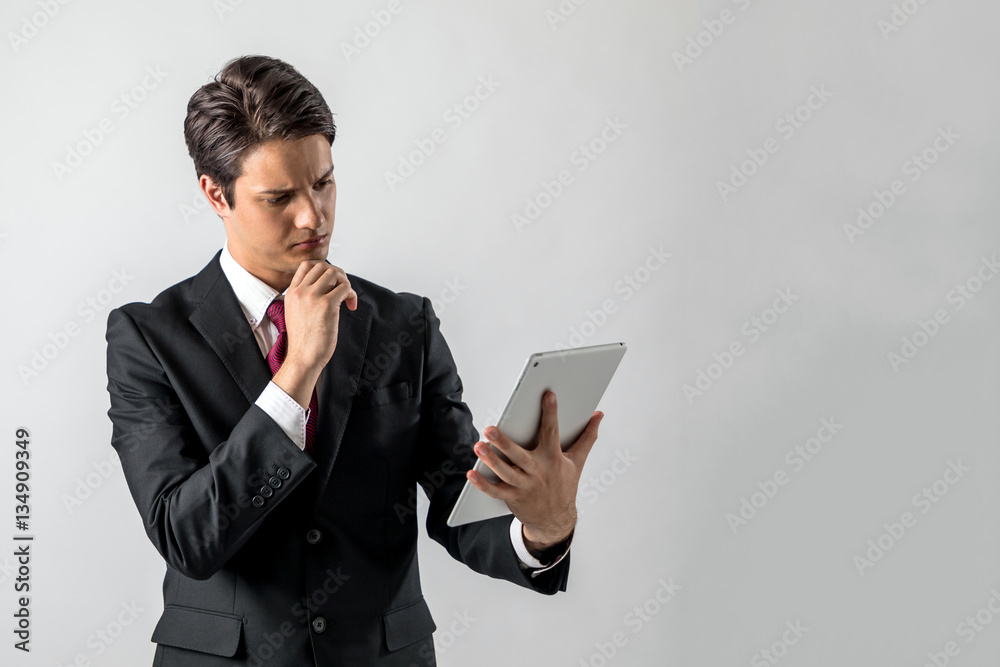 young businessman holding tablet PC and thinking something on white background young businessman holding tablet PC and thinking something on white background
