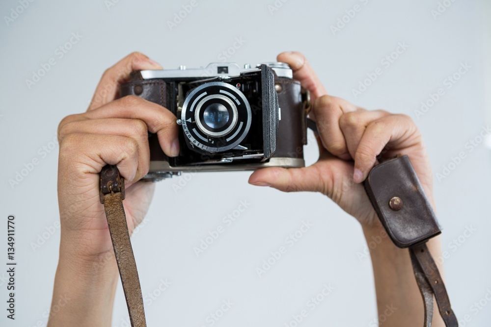 Close-up of female photographer holding old fashioned camera - obrazy, fototapety, plakaty 