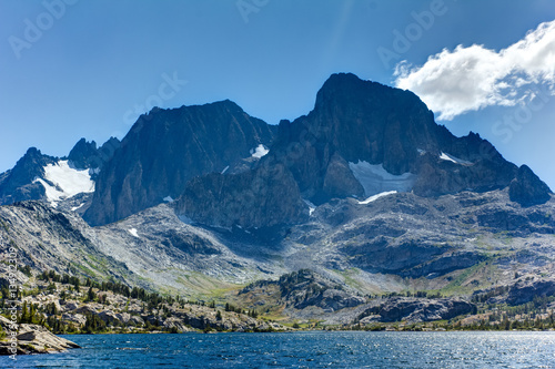 Tall granite peak rises over a blue alpine lake in the high sierra © Jeremy Francis