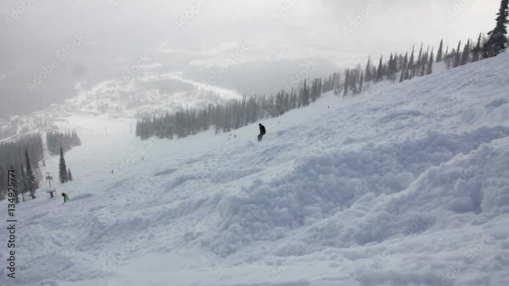 Snowboarders on the top of a mountain begins the descent Snowboarders on the top of a mountain begins the descent