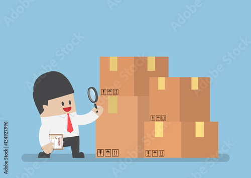 Businessman checking parcel box by magnifying glass