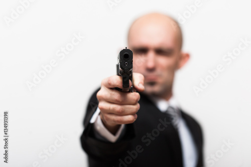 Man like agent 007 in Business suit. Gun in focus. white background