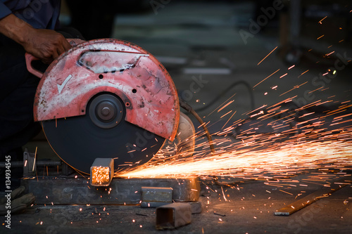 Workers use machine for cutting metal with spark light.