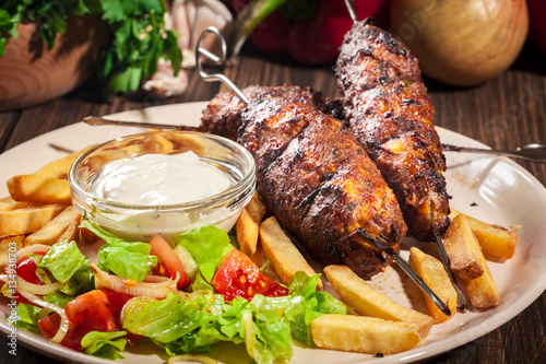 Grilled shish kebab served with fried chips and salad photo