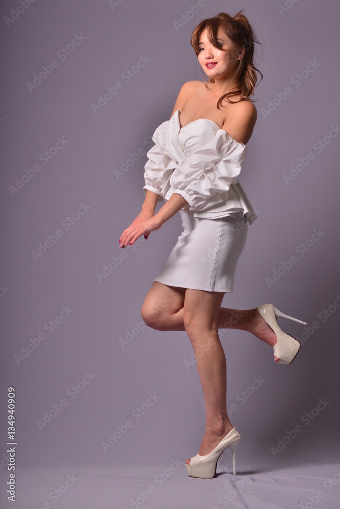 Beautiful model with long curly hair posing in an elegant Classic evening dress in the studio Beautiful model with long curly hair posing in an elegant Classic evening dress in the studio