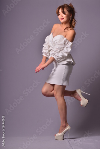 Beautiful model with long curly hair posing in an elegant Classic evening dress in the studio
