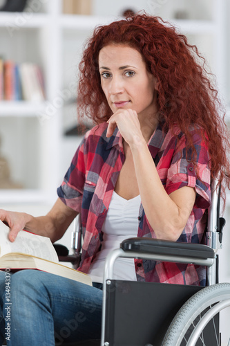 disabilty and handicap young disabled woman on wheelchair reads book photo