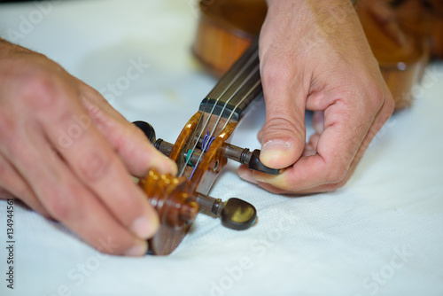 Obraz na plátně Man adjusting strings on violin