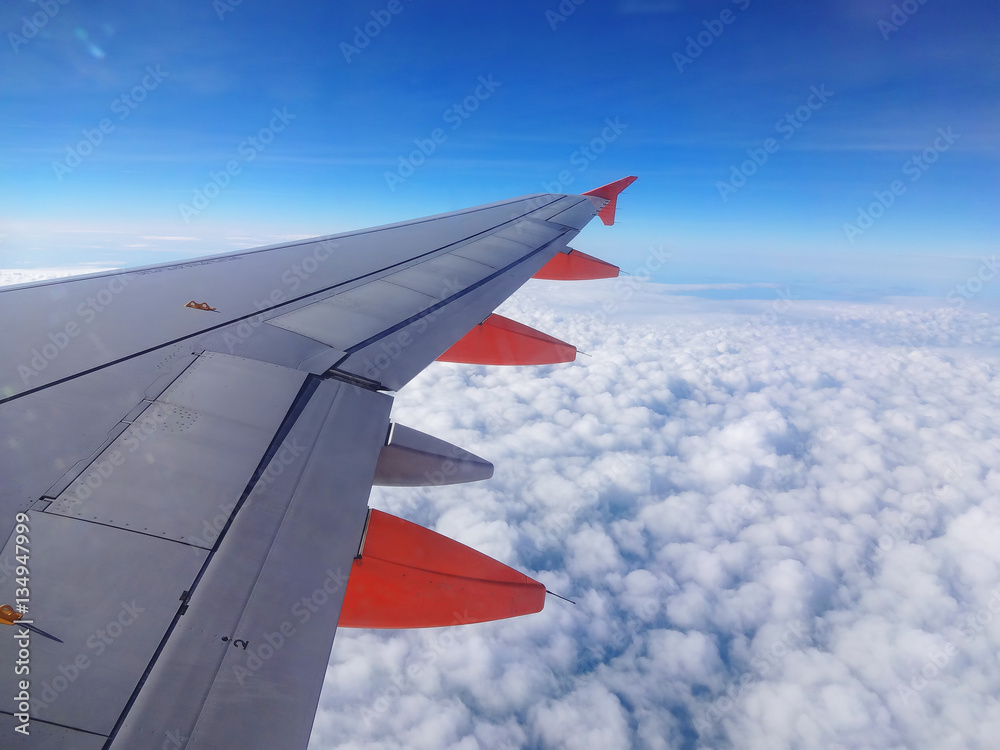 Commercial jet aircraft wing flying above the clouds