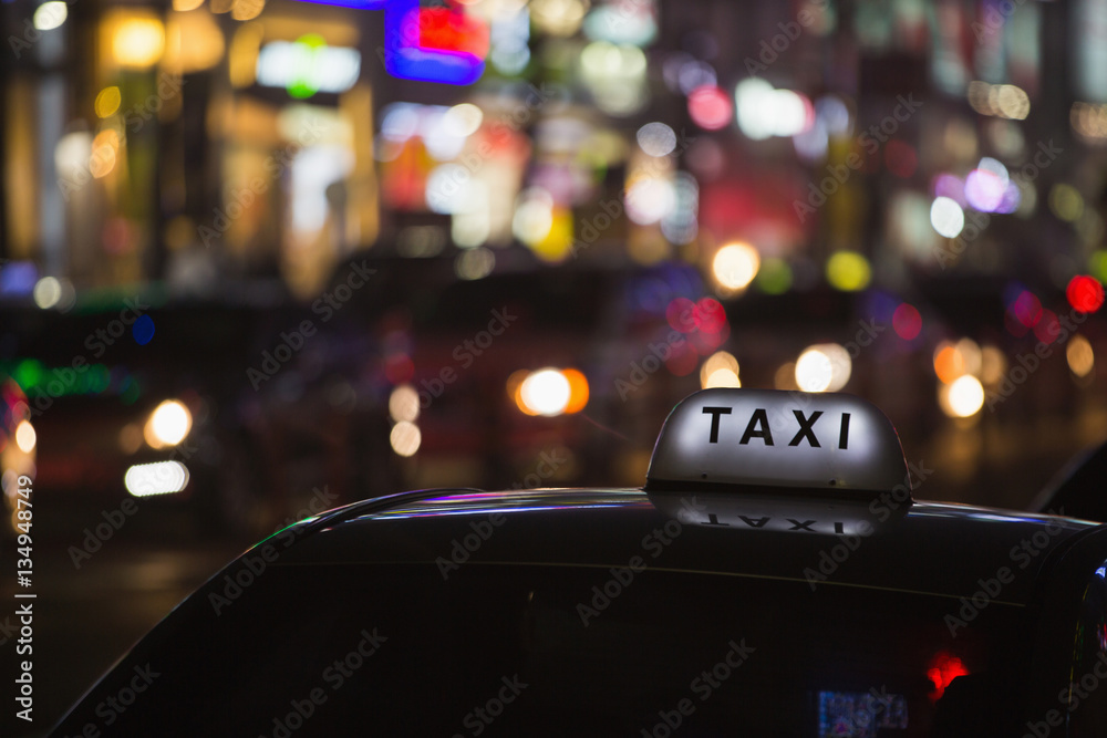 Naklejka premium Dach taksówki na tle miasta nocą neony