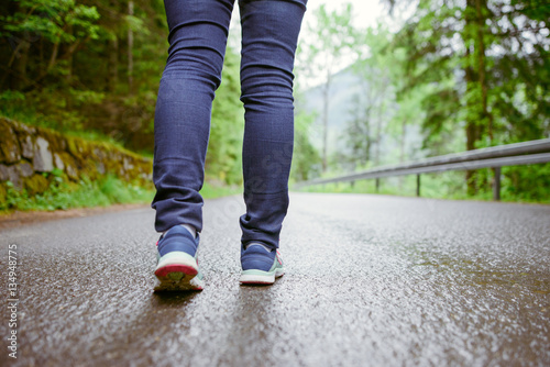 woman runner legs training on asphalt trail in the park