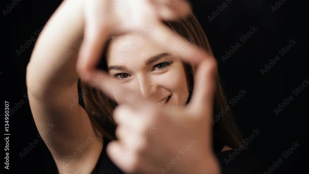 Womans hands coming into focus framing a shot - black background