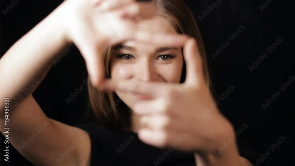 Womans hands coming into focus framing a shot - black background Womans hands coming into focus framing a shot - black background