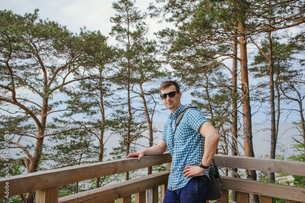 Fototapeta premium man sitting on the wooden stairs in park and smiling