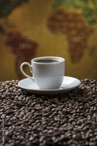 Cup of Coffee and coffee beans / Composition with cup of coffee and coffee beans with a vintage map on the background