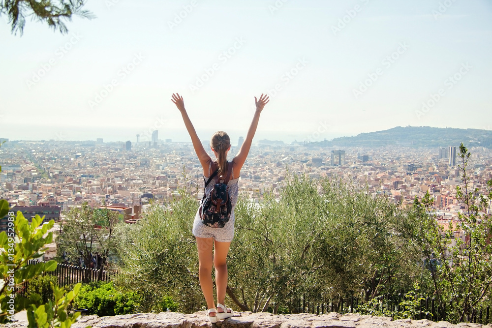 Young girl tourist with a backpack looking at a panoramic view of the city Barcelona, Spain Young girl tourist with a backpack looking at a panoramic view of the city Barcelona, Spain