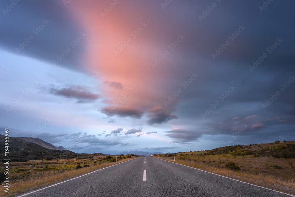 Driving on an empty asphalt road at sunset