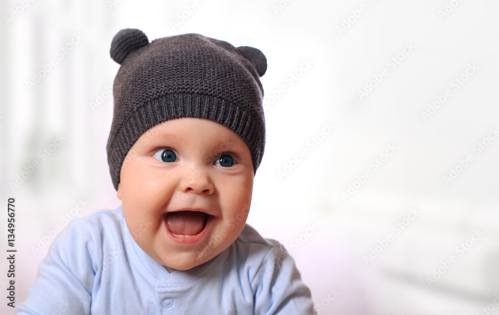 Baby in the hat smiling while sitting in bed Baby in the hat smiling while sitting in bed