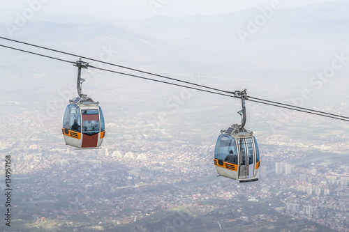 Close photo of cable car on high, with city in the background © viktormicevsk95