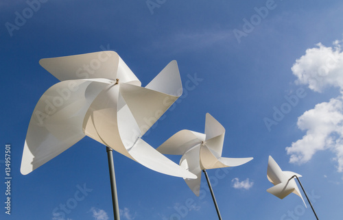 White pinwheel and windmill with blue sky and white cloud background, symbol of happiness photo