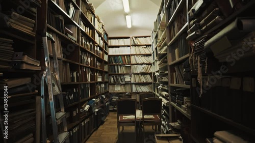 Fluorescent bulbs lights up in an old style library interior. Books and folders