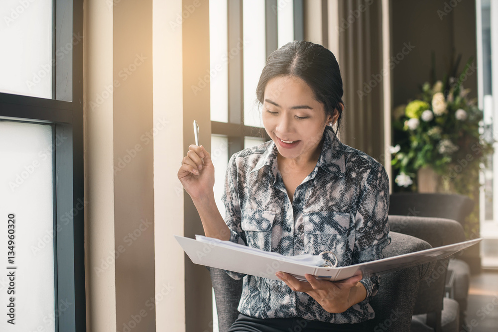 Happy young business woman working at desk typing on a document. Happy young business woman working at desk typing on a document.