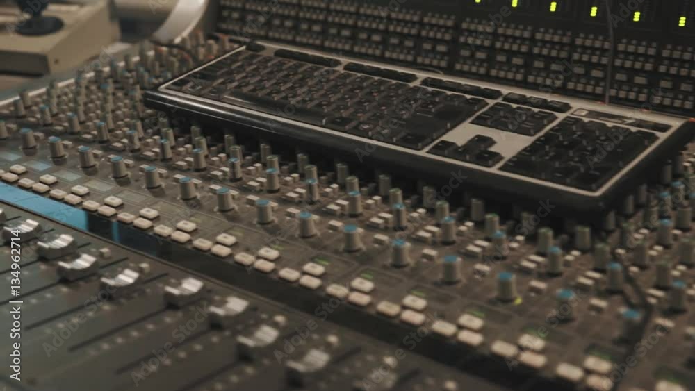 Close up dolly shot of the computer keyboard laying on music mixing console Close up dolly shot of the computer keyboard laying on music mixing console