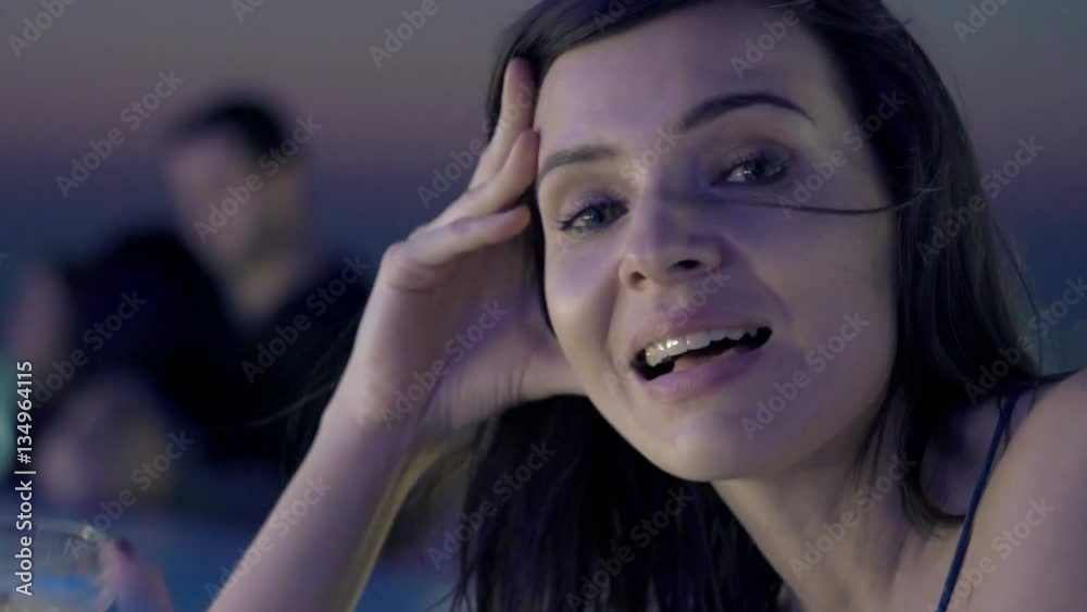 Young, happy woman flirting, talking to camera in bar at night
Young, happy woman flirting, talking to camera in bar at night