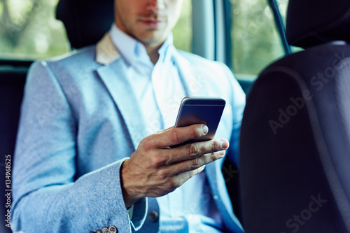 Man with mobile phone in hand sitting in the car