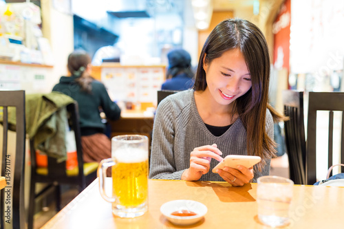 Woman using mobile phone in Japanese ramen shop