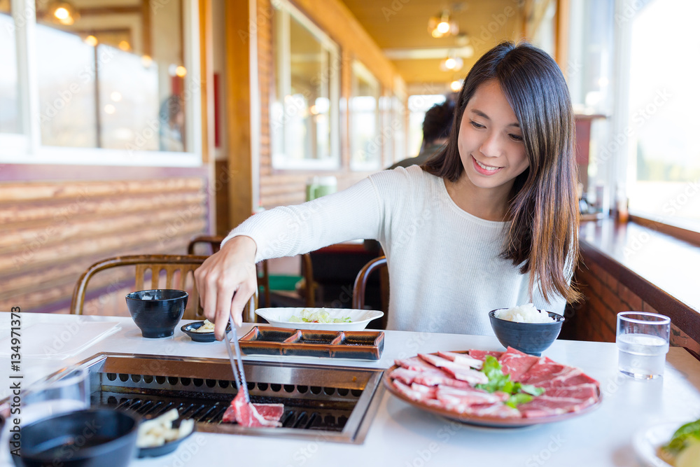 Woman eating barbecue beef in Japanese restaurant