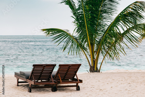 Sunbeds on sand beach at tropical island resort