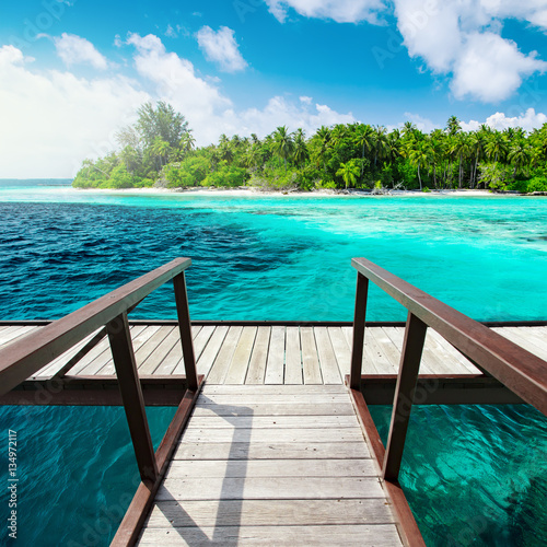 Pier with railing at tropical island and coral reef © Ivan Kurmyshov