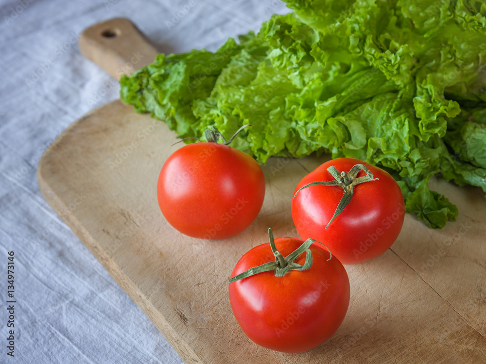 Tomatoes and lettuce on a wooden background.
