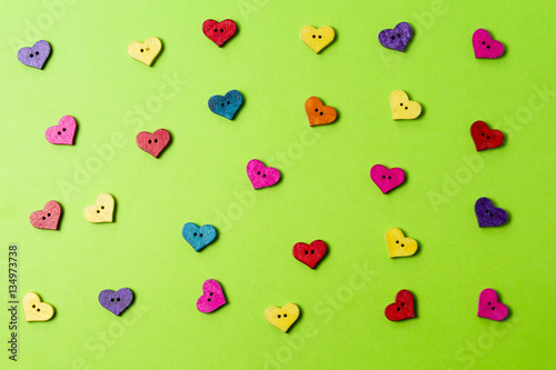 Colorful wooden heart shaped buttons on greenery background