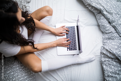 Close up of woman with laptop in bed