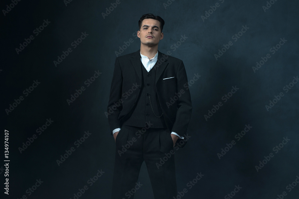 Retro 1920s english style gangster in suit against gray wall. Retro 1920s english style gangster in suit against gray wall.