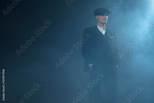 Valokuva Retro 1920s english gangster wearing suit and flat cap standing