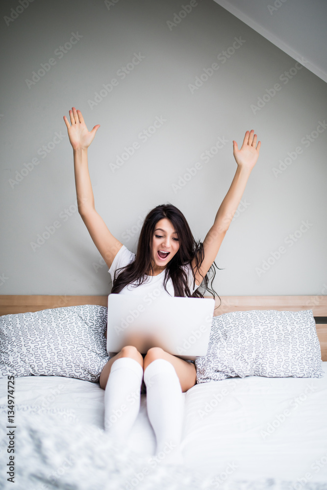 Woman with victory emotions with laptop in bed Woman with victory emotions with laptop in bed