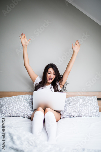 Woman with victory emotions with laptop in bed