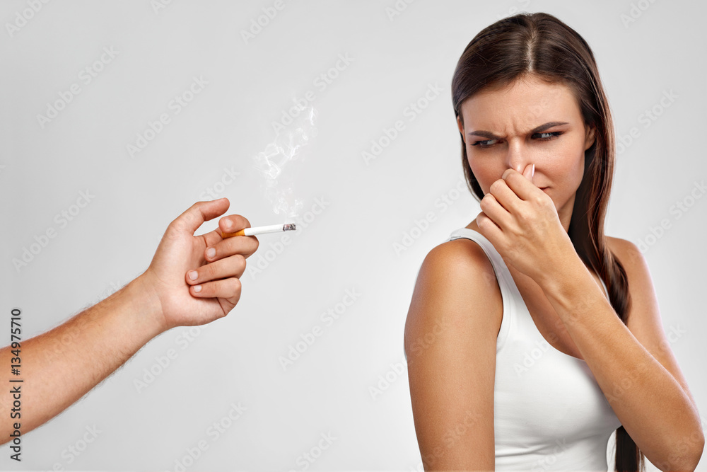 Smoking. Beautiful Woman Holding Nose, Smelling Cigarette Smell Stock