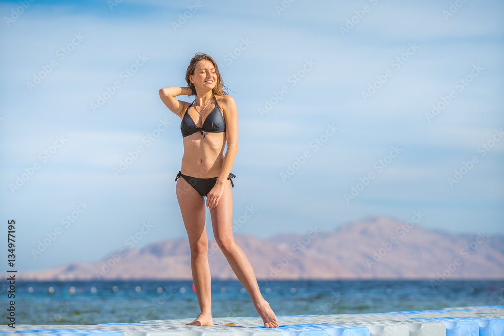 The woman in a swimsuit stand on the background of the mountain