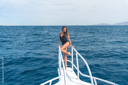 The cute woman stand in the yacht on the sea background