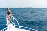 The young woman stand in the yacht on the sea background