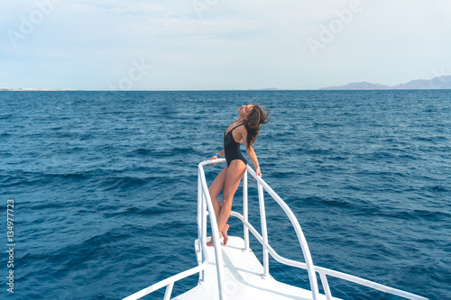 The beautiful woman stand in the yacht on the sea background