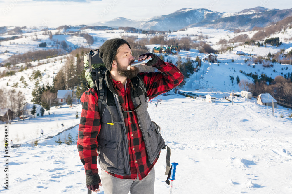 Man drinking from a hip flask on  snowy mountain
