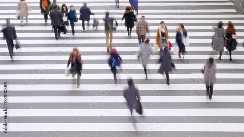Time-lapse of crowd of people crossing in crosswalk.
