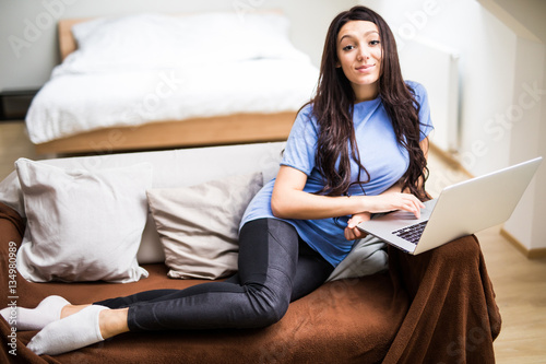 casual woman using her laptop while sitting on couch and working.